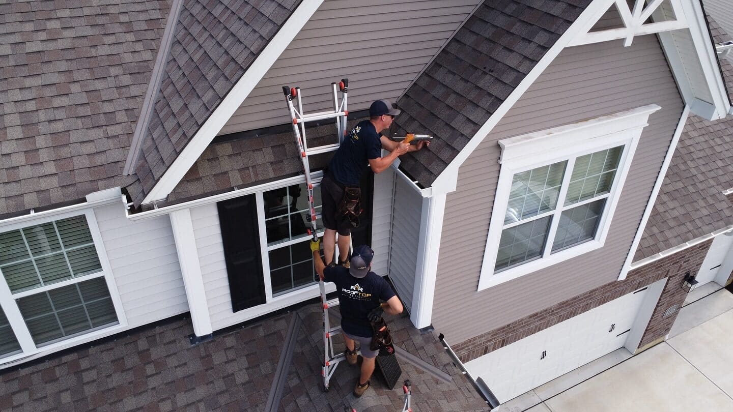 Rooftop Relief crew inspecting fascia and trim from a ladder on an Oakley area home