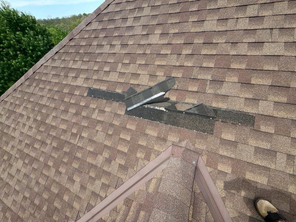 Hail damage on Cincinnati asphalt shingle roof — torn shingle tabs exposing dark underlayment after spring storm